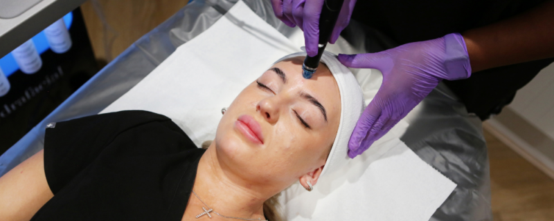 woman getting a hydrafacial treatment at fiji skin clinic with purple gloves